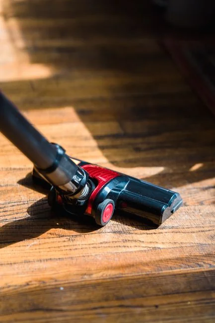 a-woman-in-a-green-shirt-and-black-gloves-vacuuming-a-gray-ottoman-5txz228u4eo